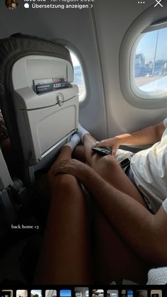 a man sitting in an airplane seat looking at his cell phone