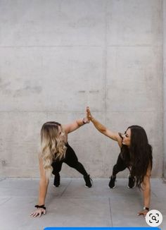 two women in black and white are doing handstand on the ground with their legs crossed