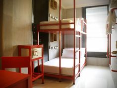 a room with bunk beds in it and a red chair next to the bed on the other side