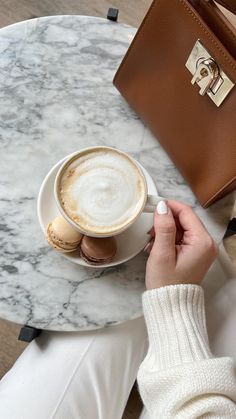 a woman sitting at a table with a cup of coffee