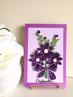 a card with purple flowers on it next to a white vase