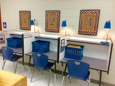 three desks with blue chairs in front of them and pictures on the wall behind them