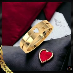 a gold ring with a red heart on it