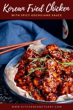 a blue plate topped with meat covered in sauce and garnished with green onions