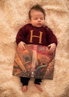 a baby is holding a harry potter book while laying on a fluffy white blanket with it's eyes closed