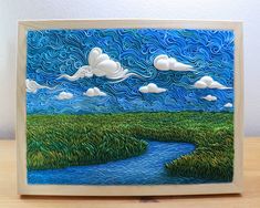 a card with an image of a river and clouds in the sky, on top of a wooden table