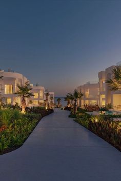 a walkway leading to several white buildings at dusk