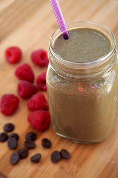 a jar filled with chocolate and raspberries on top of a wooden cutting board