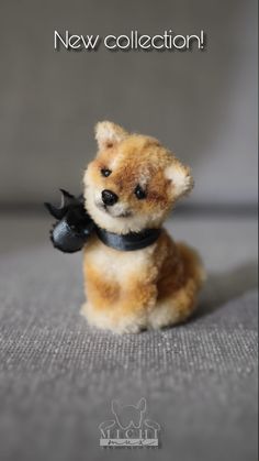 a small teddy bear with a black collar holding a toy bat in it's paws