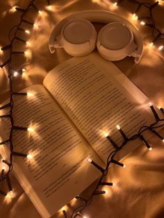 an open book with headphones on top of it and some lights in the background