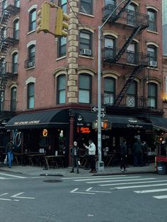 people are standing at an intersection in front of a brick building