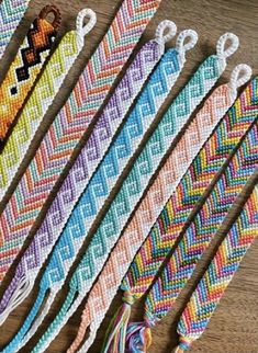 six different colored bracelets with tassels on them sitting on a table next to each other