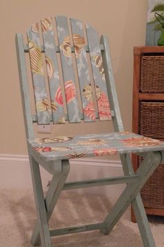 a blue wooden chair with seashells painted on it's back and seat