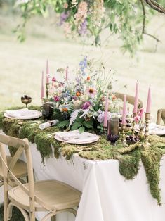 the table is set with flowers and candles for an outdoor dinner party or wedding reception