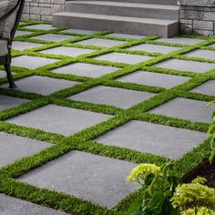 a chair sitting on top of a grass covered patio next to stairs and steps in front of a building