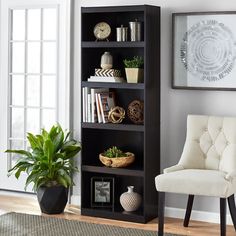 a white chair sitting in front of a black book shelf filled with lots of books