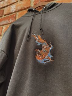 "Koi Fish Embroidered Hoodie -Embroidered on a cotton/polyester blend hoodie, this design is simple and minimalistic, perfect for every outfit! -Embroidery design measures 6\" x 3\" -See product pictures for shirt sizing chart. -Hanes/Gildan Brand depending on availability. -All sweatshirts are handmade on an embroidery machine so there may be slight differences, but we only sell the shirts that meet our high-quality standards. -To maintain the quality of your shirt and the embroidery design mak Koi Fish Hoodie, Cotton Hoodie With Embroidered Graphics For Streetwear, Black Embroidered Hooded Hoodie, Cotton Hoodie With Embroidered Patch For Streetwear, Embroidered Patch Cotton Sweatshirt For Streetwear, Embroidered Cotton Sweatshirt For Streetwear, Embroidered Graphics Hoodie For Streetwear, Embroidered Long Sleeve Hoodie For Streetwear, Long Sleeve Hoodie With Embroidered Graphics For Streetwear