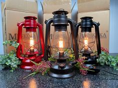 three red and black lanterns sitting on top of a table next to boxes filled with flowers