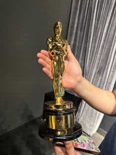 a person holding an oscar statue in their hand with the award on it's pedestal