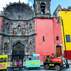 an old church with colorful buildings and children's toys on the street in front