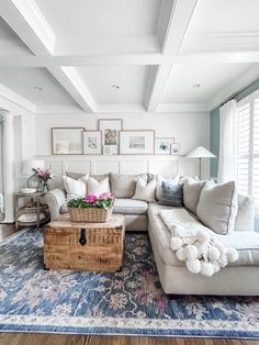 a living room filled with furniture and flowers on top of a blue rug in front of a window