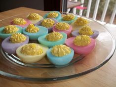 a glass plate filled with deviled eggs on top of a wooden table