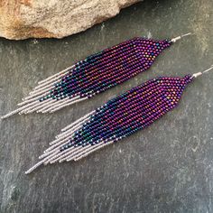 two pairs of beaded earrings sitting next to each other on top of a rock