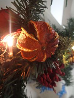 an orange cut in half sitting on top of a christmas tree next to a lit candle