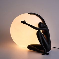 a black figure sitting in front of a white light