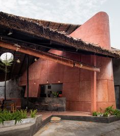 the outside of a house with a thatched roof and an outdoor kitchen area in front of it