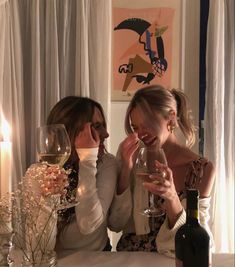 two women sitting at a table drinking wine