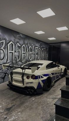 a white sports car parked in front of a graffiti covered wall with the word babee forte on it