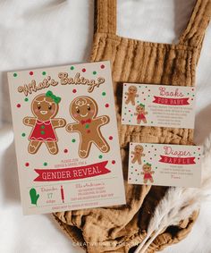 two gingerbread cookies are on top of a brown bag and next to some cards