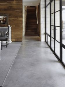 a long hallway leading to a living room with white furniture and large windows on both sides