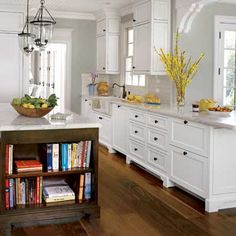 a kitchen with white cabinets and an island in the center is surrounded by bookshelves