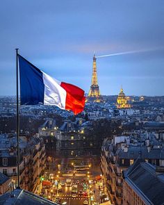 the flag of france is flying high in the sky over an urban area at night