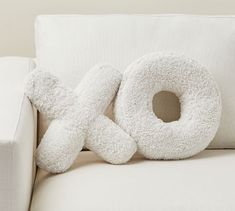 a white stuffed animal sitting on top of a couch next to a pillow that says x