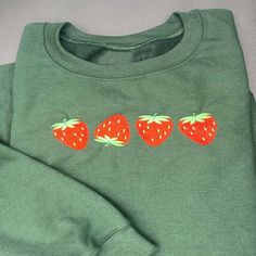 three strawberries embroidered on the back of a green shirt