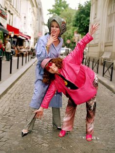 two women are posing for a photo on the street with their hands in the air