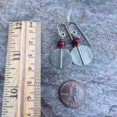 Two carnelian stones have been wrapped in sterling silver. The redding orange stones are accented by textured sterling silver discs. The earrings dangle from handmade sterling silver earwires. The silver has been oxidized and polished to create an aged patina finish.Be sure to see all photos and video for size and color reference. Carnelian: About 6mmTotal Earring Length (Including Earwire): About 1.5"Earring Weight: About 2.4 grams per one earring Nickel-free Red Carnelian Earrings, Carnelian Round Earrings With Ear Wire, Silver Carnelian Earrings, Carnelian Wire Wrapped Earrings As Gift, Carnelian Wire Wrapped Earrings For Gift, Silver Round Carnelian Earrings, Gift Carnelian Wire Wrapped Earrings, Silver Carnelian Jewelry With Ear Wire, Adjustable Nickel-free Carnelian Jewelry