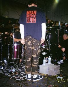 a man standing on top of a floor next to a drum set in front of him