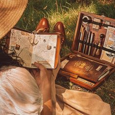 a person sitting on the grass with an open book in front of them and other items