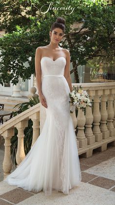 a woman in a white wedding dress standing on a balcony with her hand on her hip