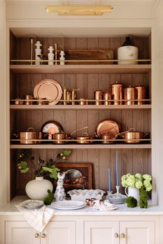 the shelves in this kitchen are filled with pots and pans, plates, and vases