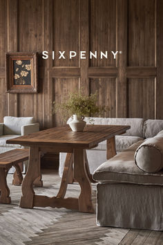 a living room with wood paneling and a table in the center surrounded by couches