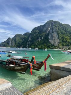 several boats are docked in the water next to some cliffs and mountains on an island