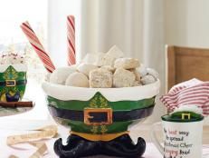 a bowl filled with marshmallows sitting on top of a table next to two mugs