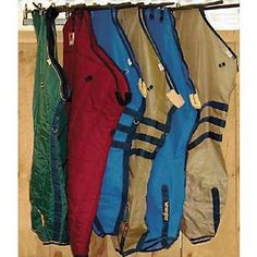 four snowboard jackets hanging on a rack in front of a window with wood flooring