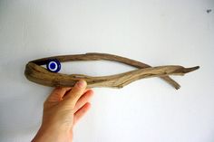 a hand holding a piece of driftwood with an evil eye on it