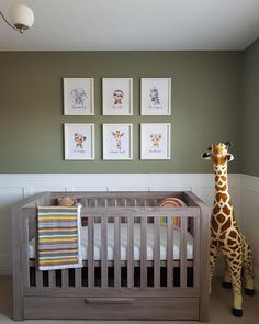 a giraffe standing next to a baby's crib in a room